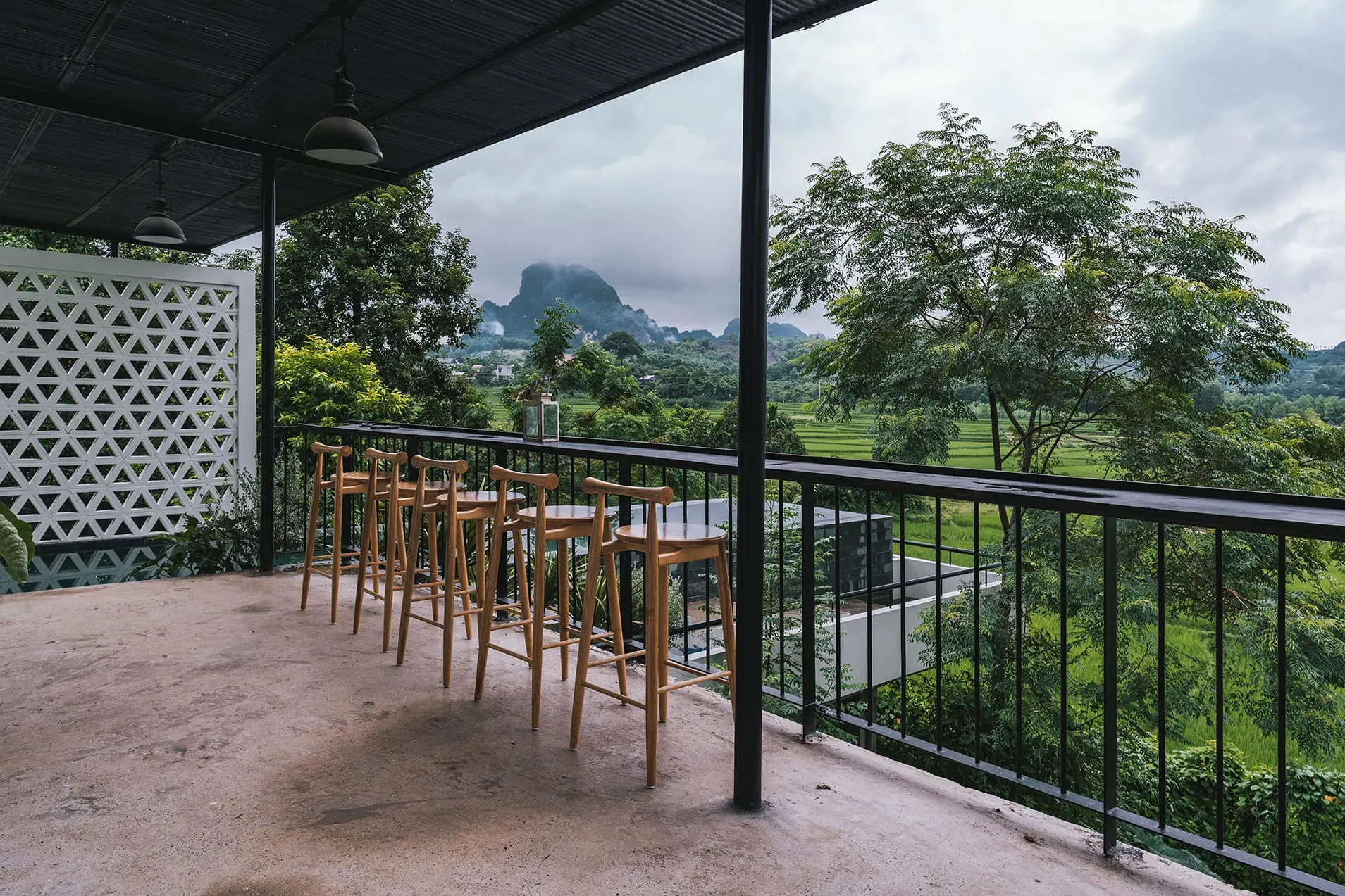 Ban công với ghế gỗ nhìn ra đồng lúa và núi đồi
